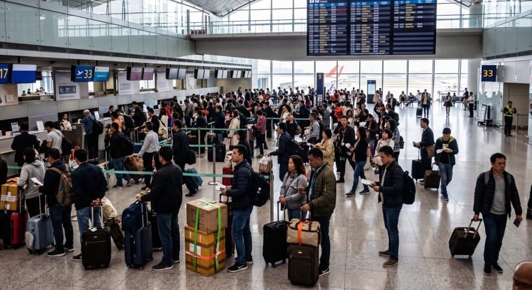 Prospective travelers queue at a generic international airport terminal. This image is a photo-illustration created with AI for illustrative purposes and does not depict specific individuals or locations related to the current advisories.